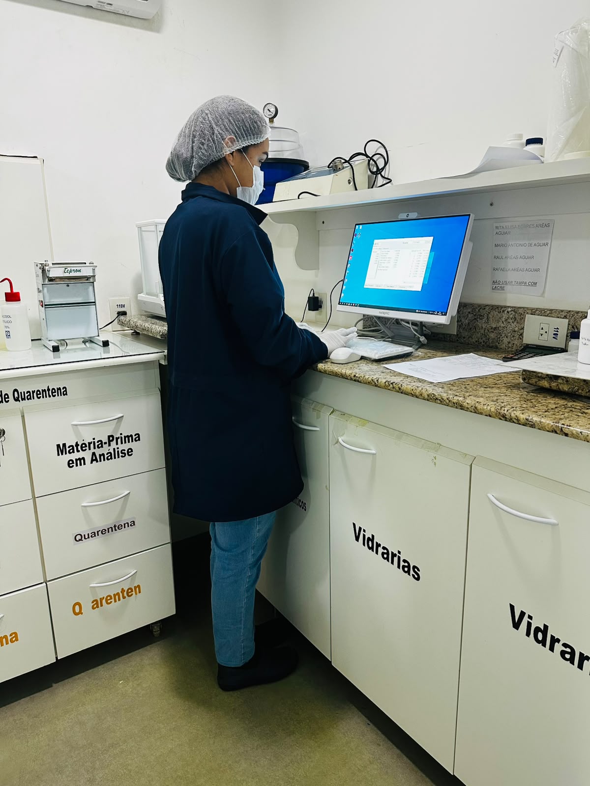 Farmacêutica conferindo a prescrição no sistema, dentro do laboratório